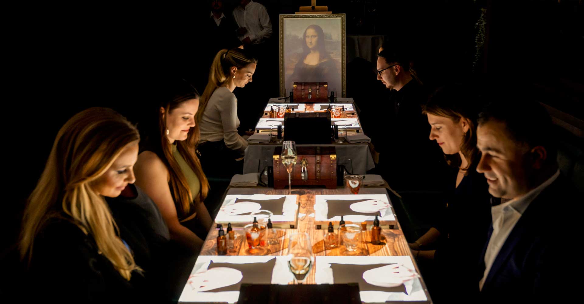 Guests dining at the glowing table beneath the Mona Lisa